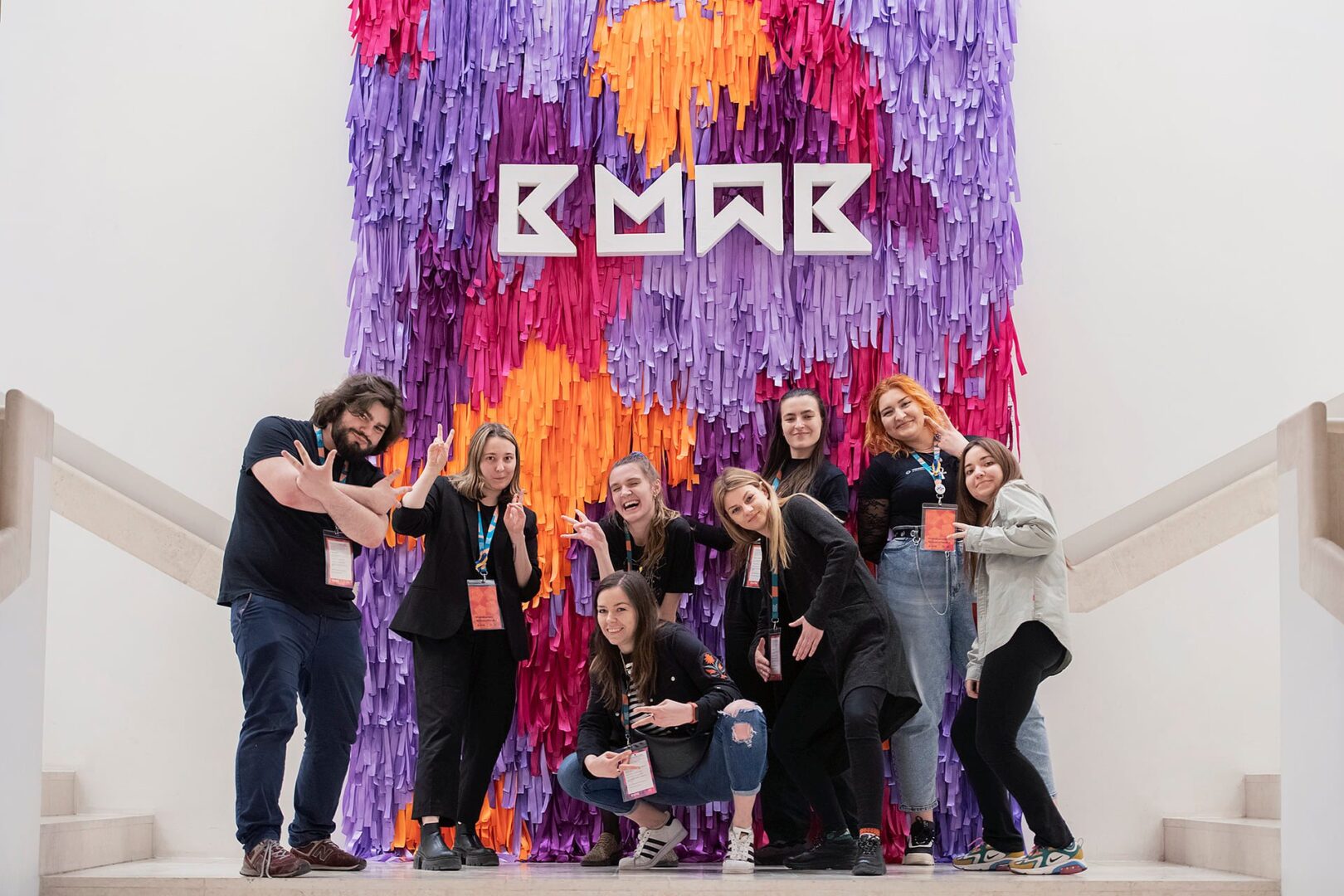 Zespół organizatorów Konferencji Marketing w Kulturze 2022. Osoby stoją na schodach, na tle kolorowej instalacji z logo Konferencji.  Fotografia: Bogna Kociumbas.
